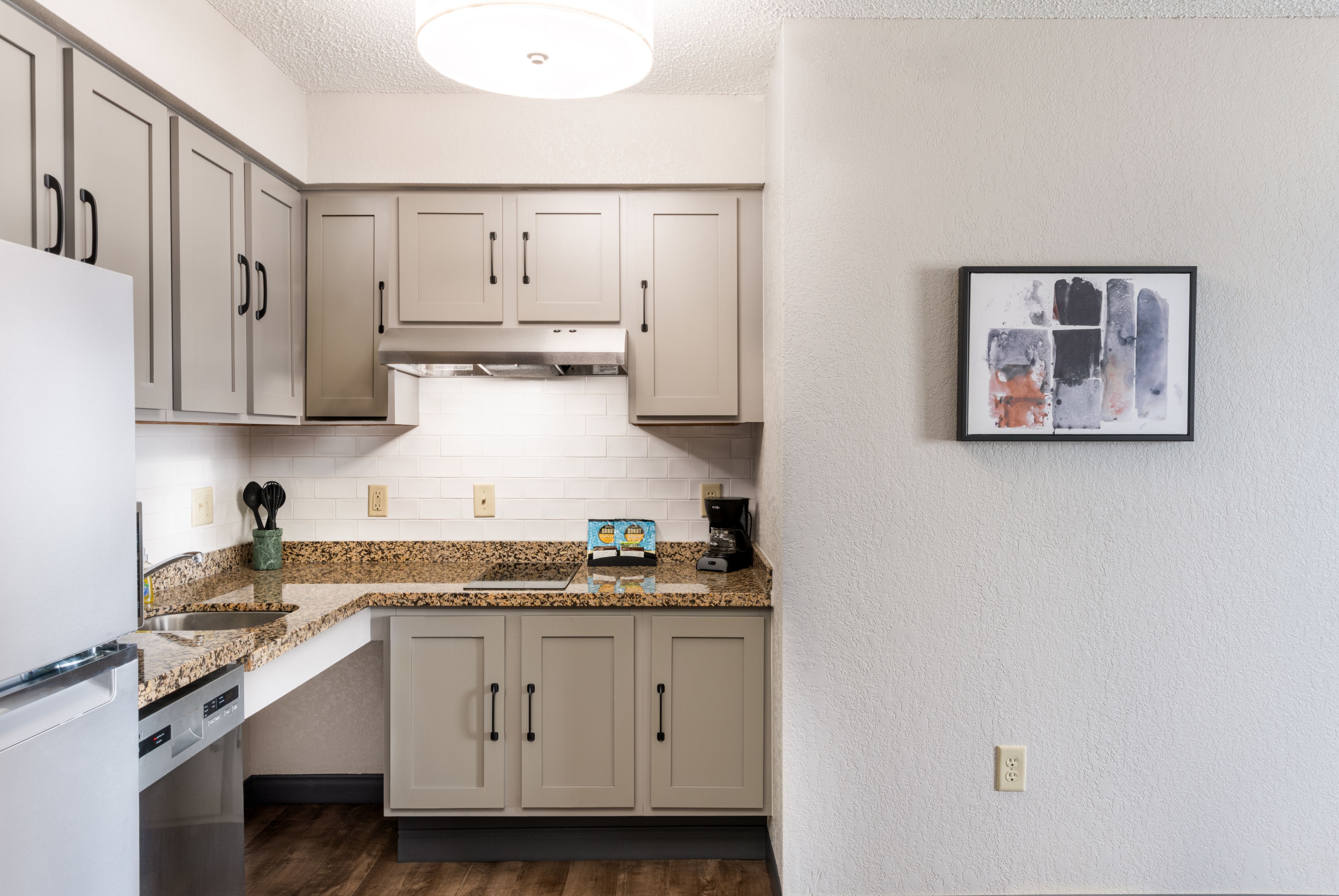 image Modern kitchen featuring gray cabinetry and granite countertops.