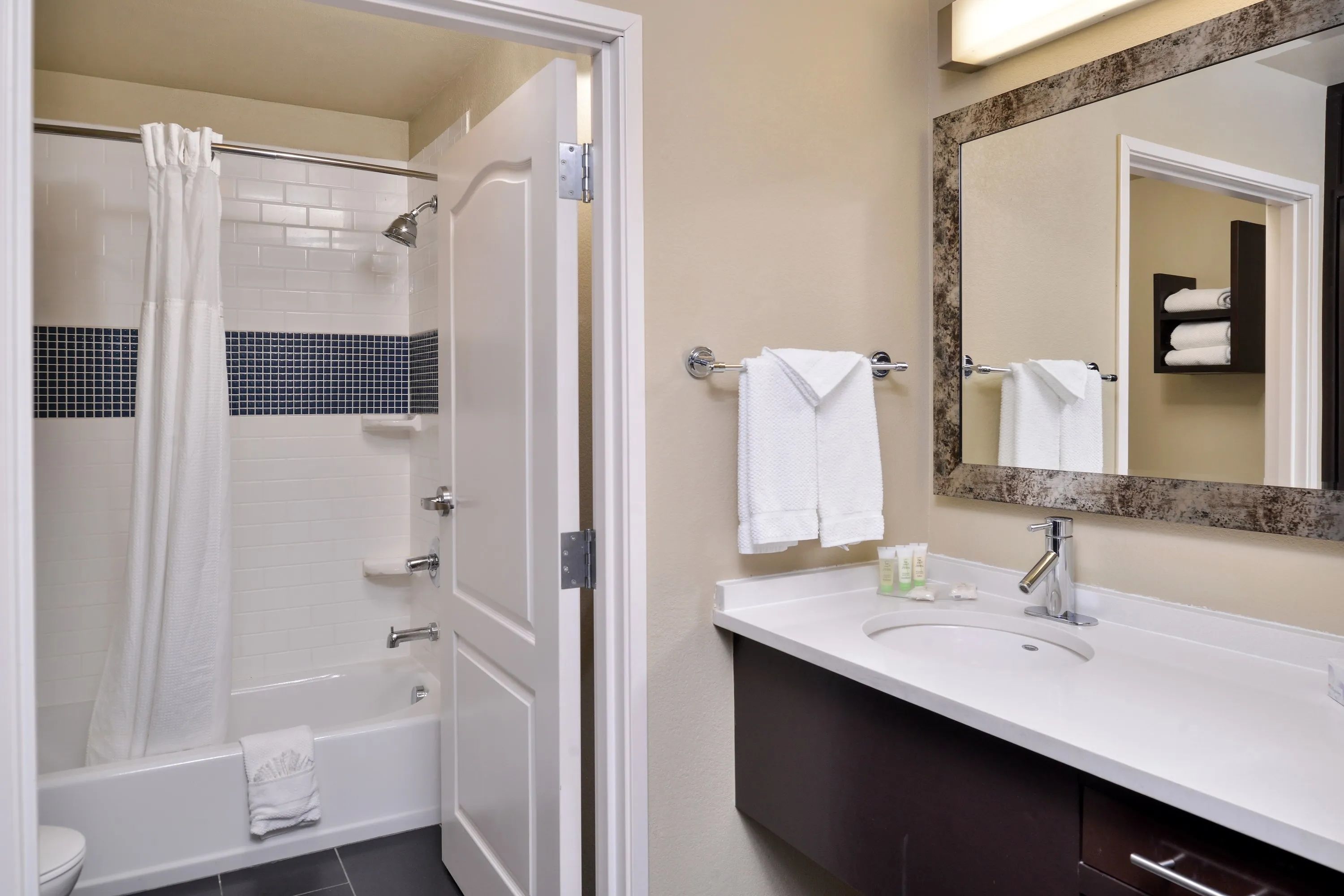 image Accessible bathroom with tub, sink, and towels.