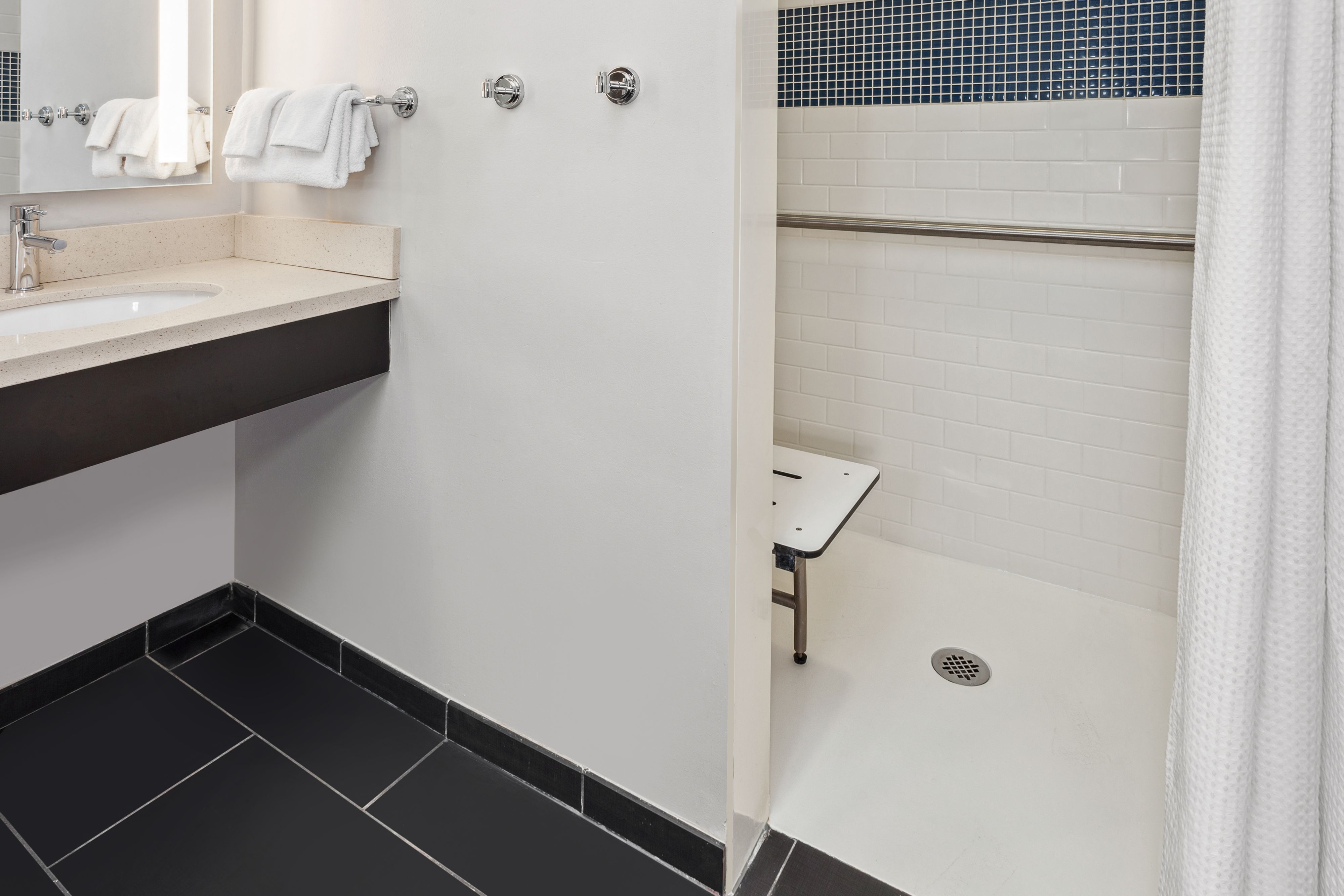 image Accessible bathroom equipped with grab bars and shower chair.