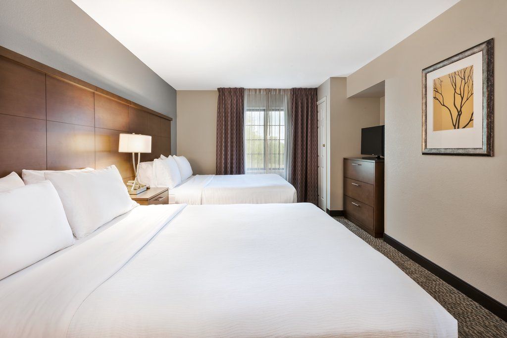 image Relax in this inviting bedroom featuring two cozy Queen beds and warm, natural light streaming through the window.