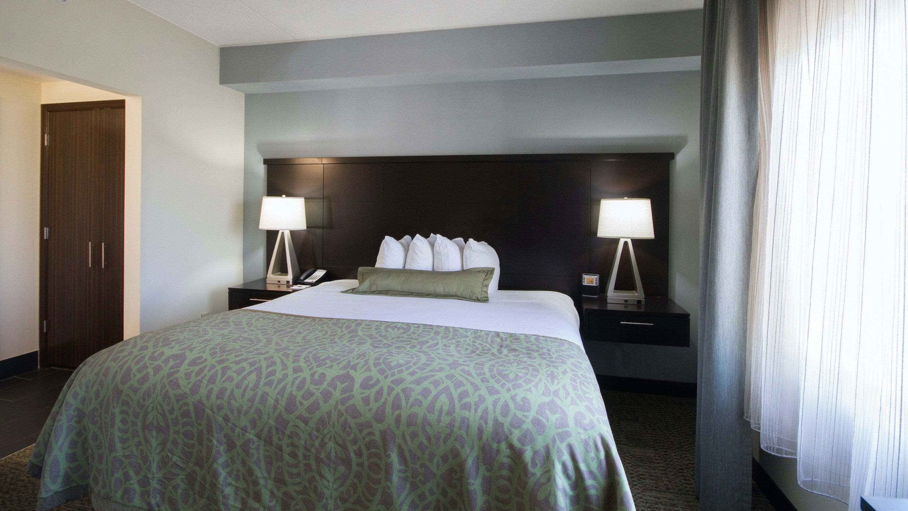 image King bed with white linens and wide clearance on both sides — fully accessible bedroom layout