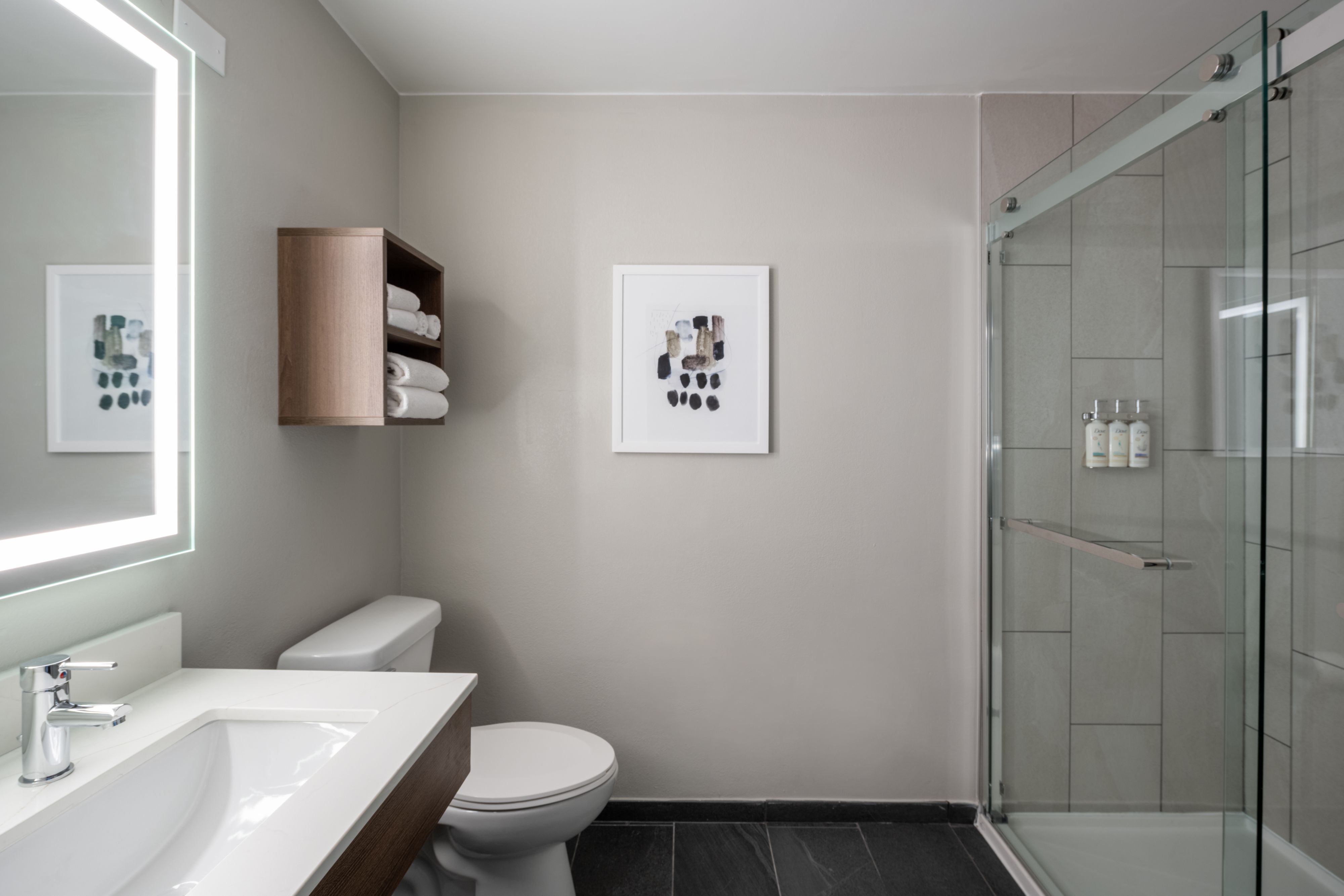 image Sleek bathroom featuring a shower, storage, and illuminated mirror.