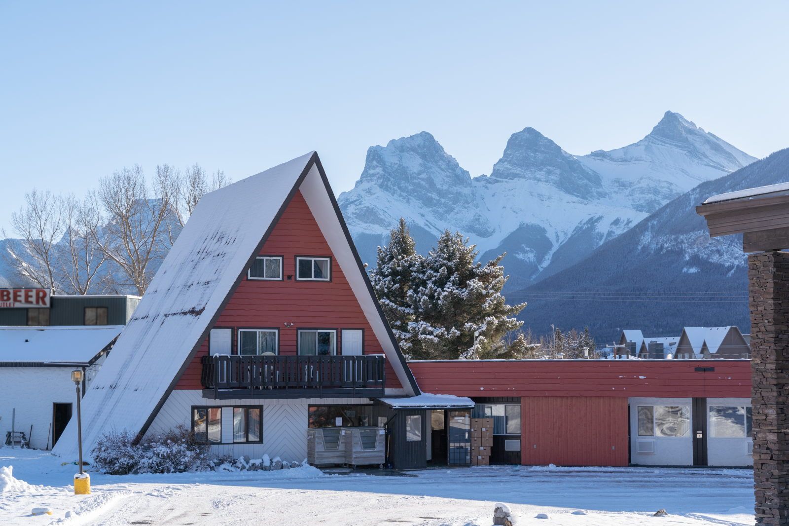 image A-frame exterior with the Three Sisters peaks rising directly behind, snow on the ground in winter