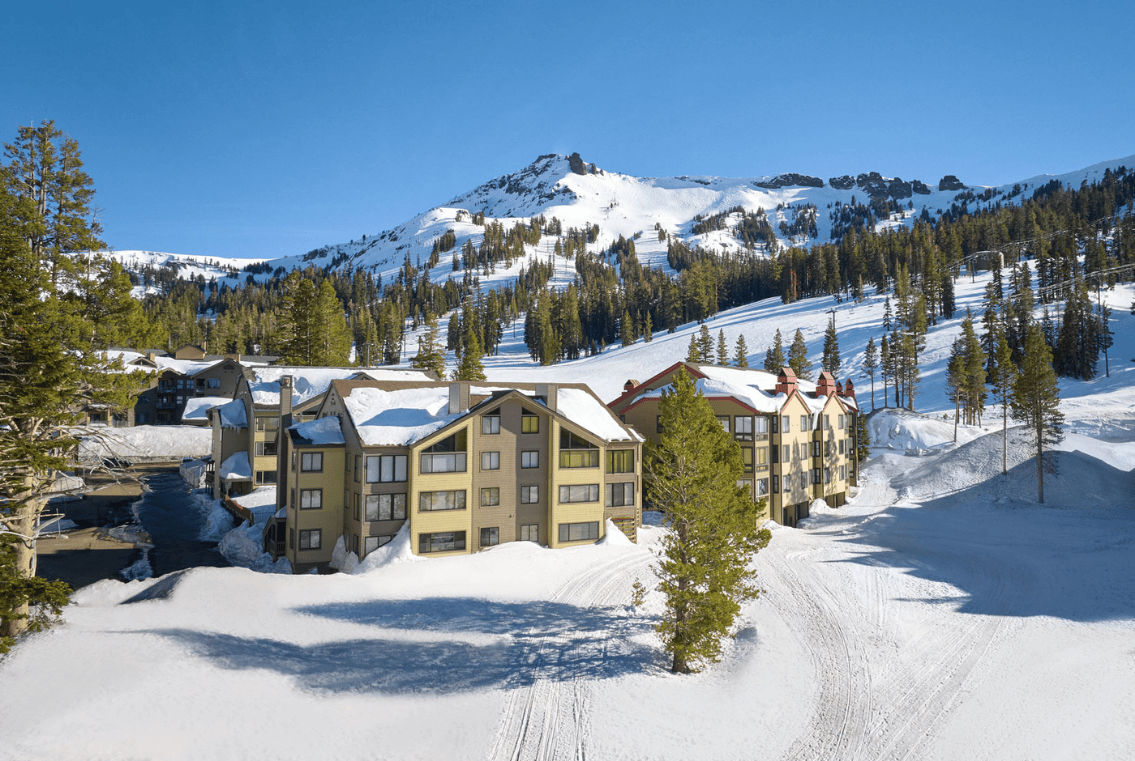 image Embrace the cozy charm of snow-laden condos nestled against the majestic winter landscape, inviting adventure at your doorstep.