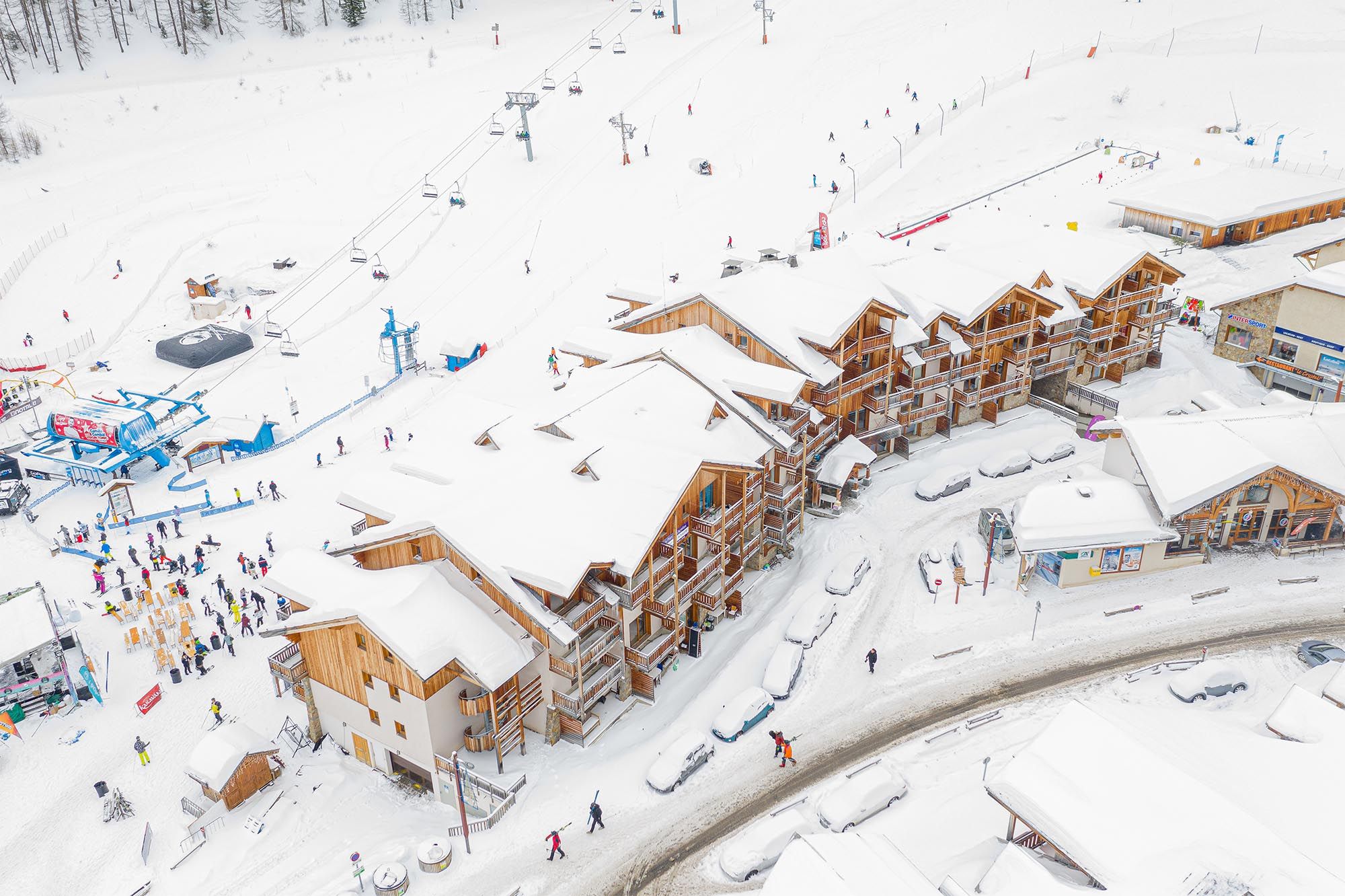 image Aerial view of the snowy site with buildings, ski lift and skiers