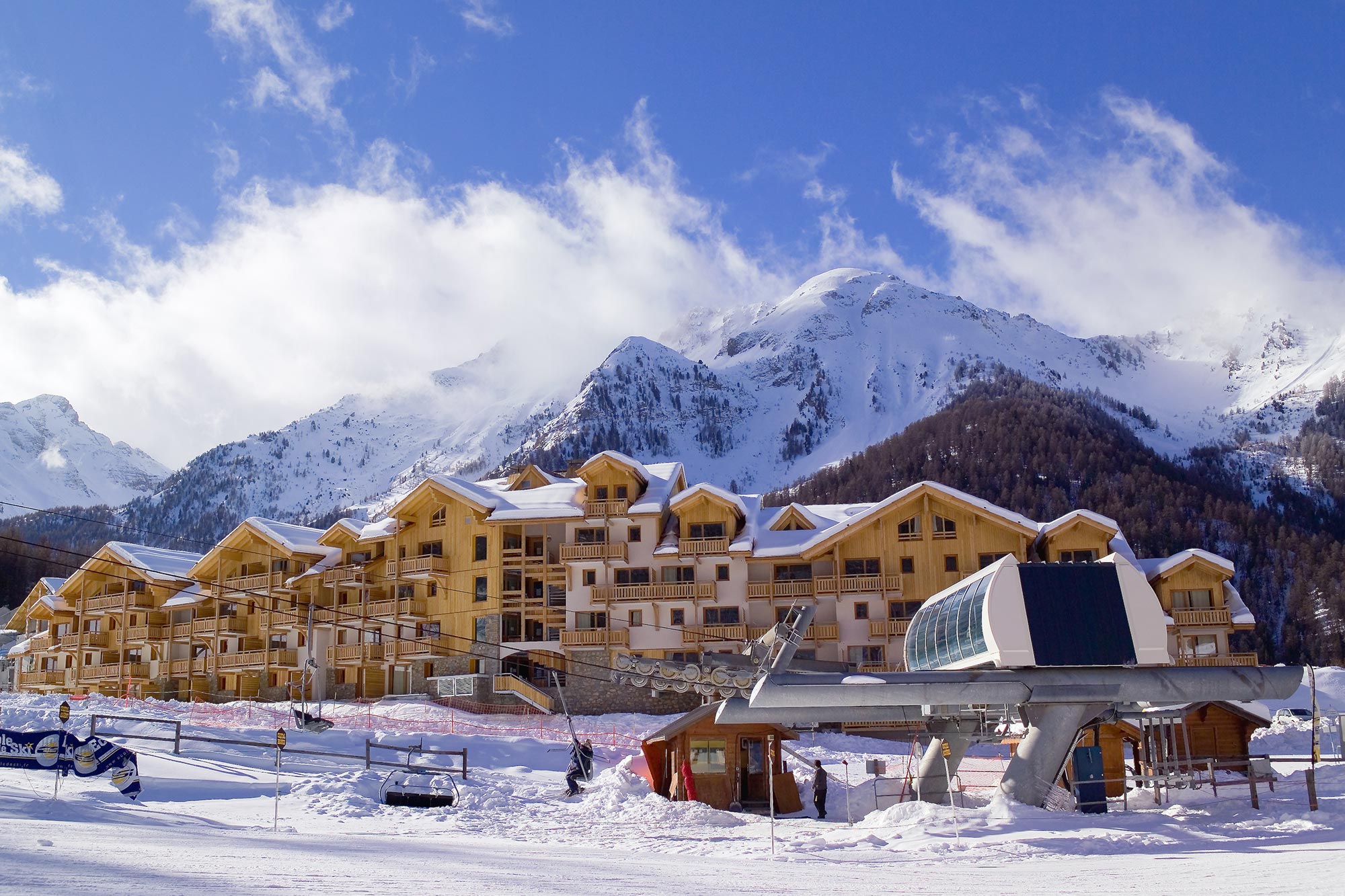 image Ski lift beside wooden buildings with mountains behind