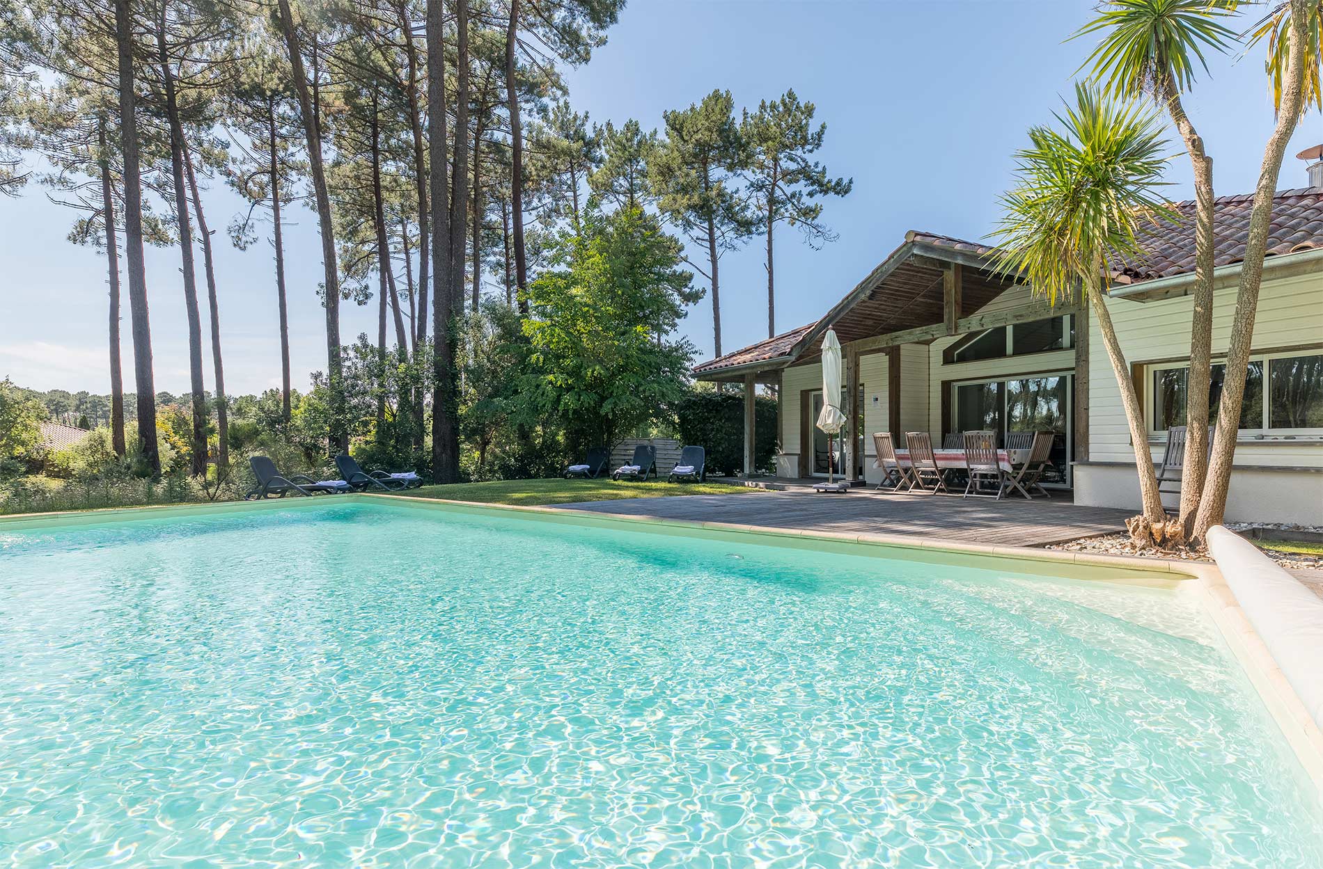 image Pool terrace, tall pine trees, villa façade, blue sky:
Soak up the Landes sunshine beside your private pool, framed by the towering pines that make Moliets one of Southwest France's most sought-after destinations.