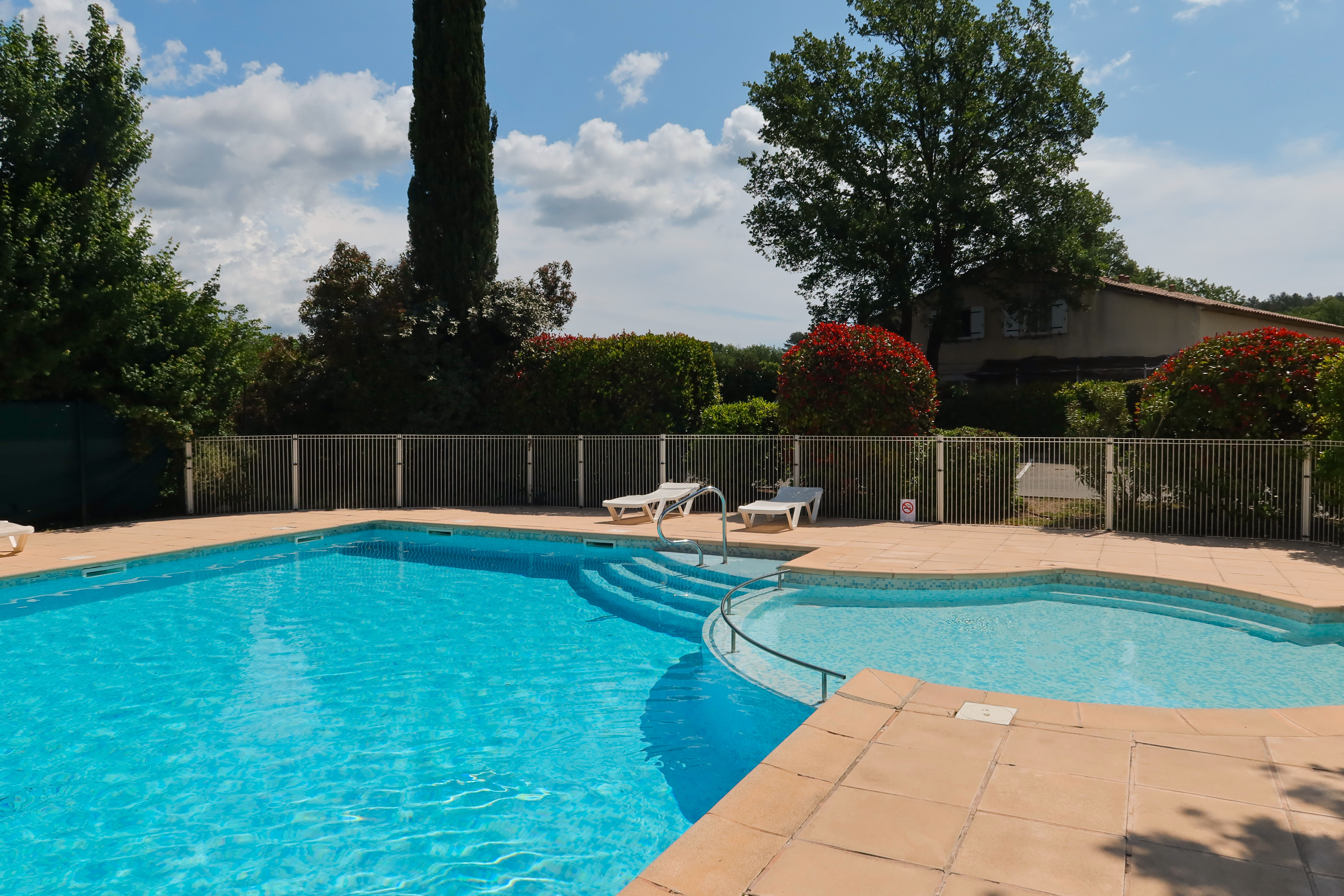 image Enjoy a leisurely swim while surrounded by beautiful landscaping and blue skies.