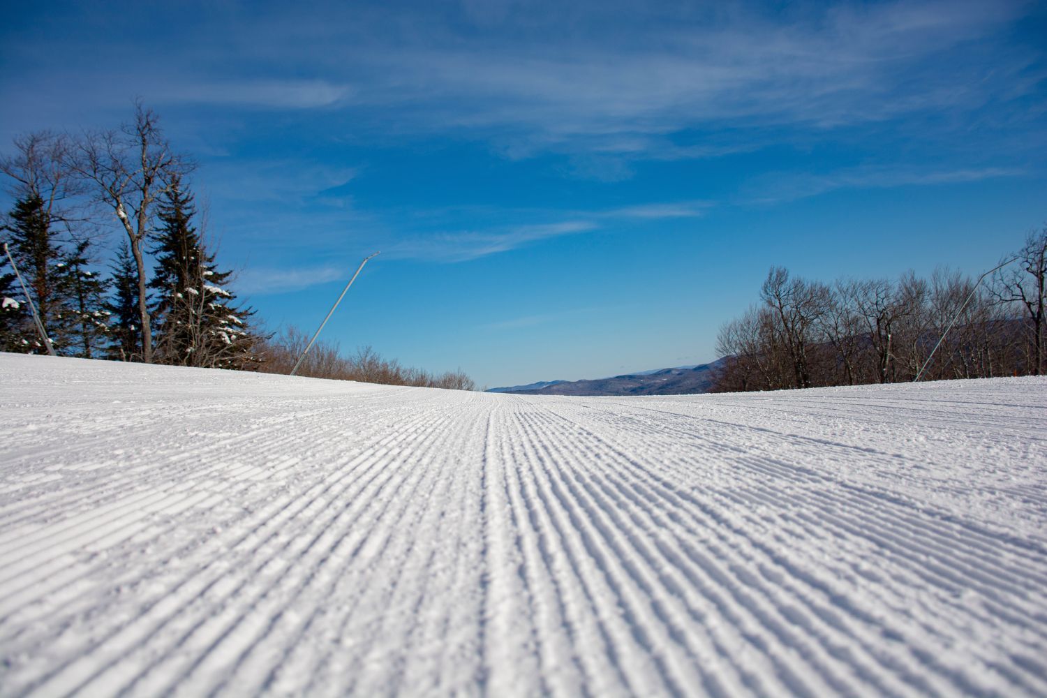 image Expansive and well-groomed slopes stretch invitingly into the distance, showcasing the perfect conditions for endless snow sports against the backdrop of tranquil, snowy Vermont terrain.
