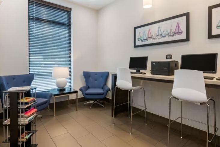 image Business center with two desktop computers, printer, and high-back seating