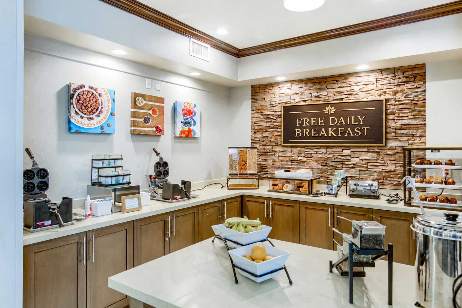 image Breakfast buffet area with waffle makers, pastries, fruit, and cereal