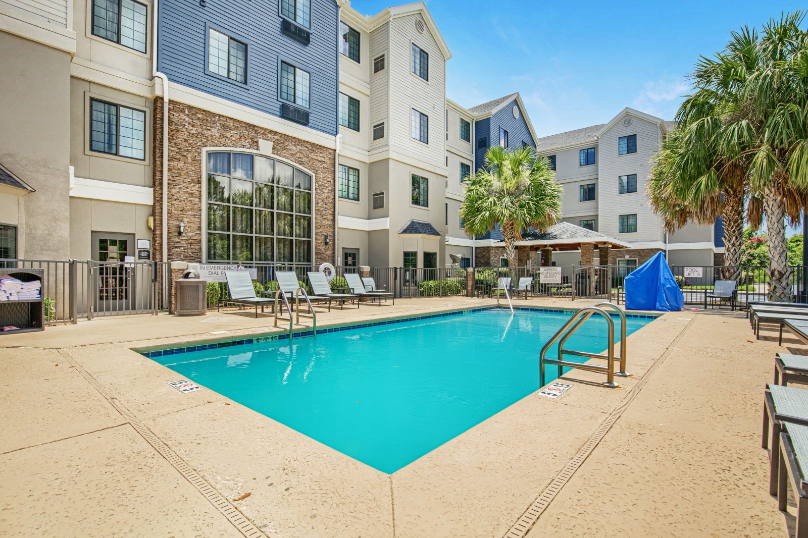 image Outdoor pool with lounge chairs, palm trees, and building facade