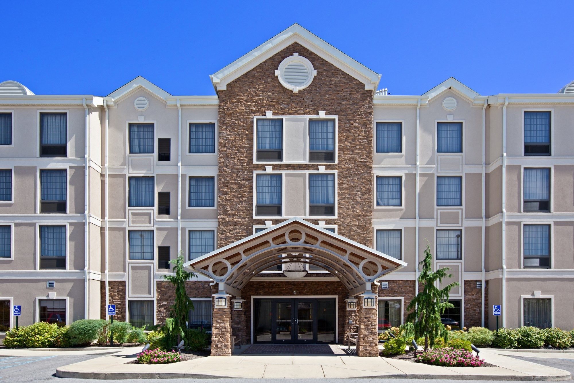 image Hotel exterior with covered entryway and landscaped front.