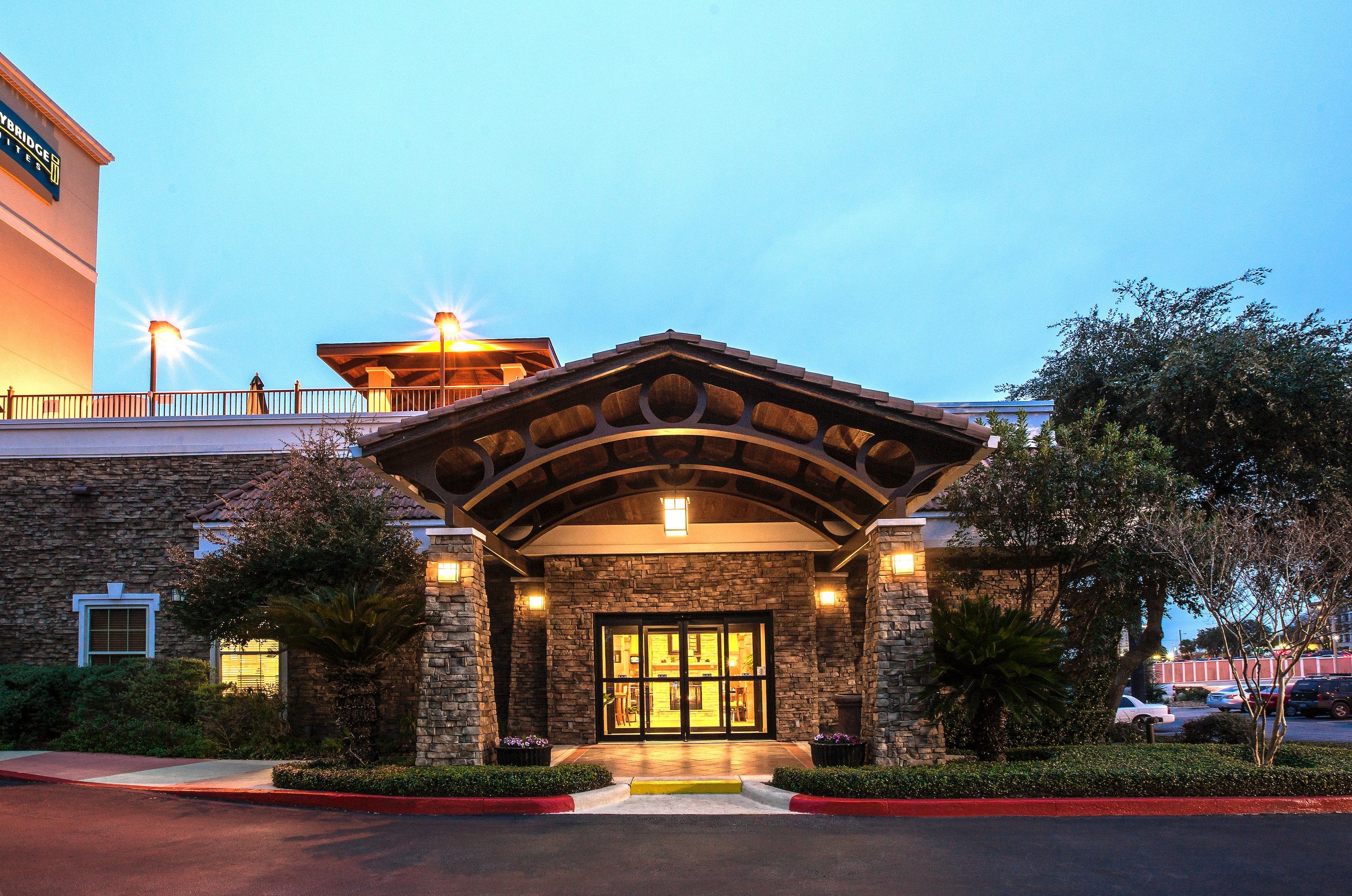 image Stone-pillared entrance with tiled portico, glass double doors, and flower planters on each side