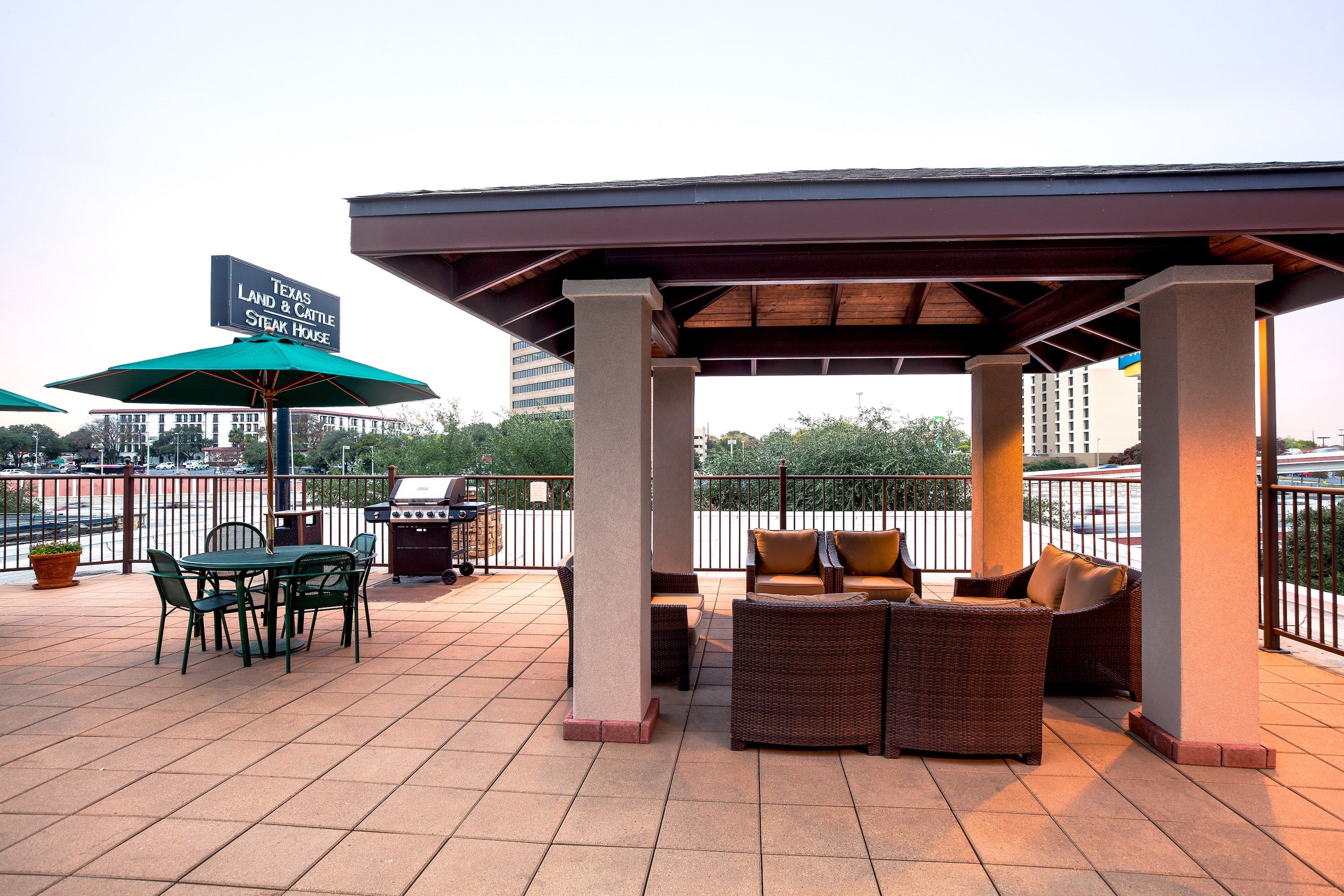 image Outdoor patio with green metal dining chairs, wicker lounge seating, and a gas grill