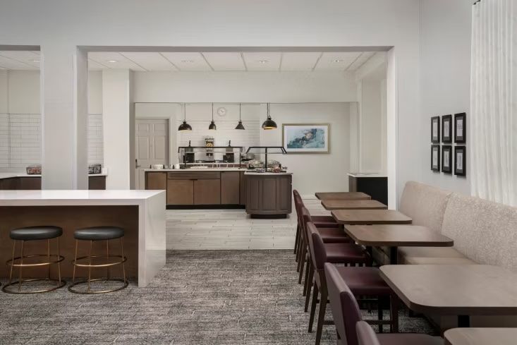 image Dining area with maroon-upholstered chairs, tan booth seating, and a service counter at the rear
