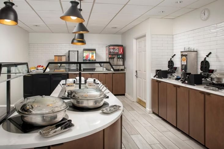image Hot breakfast buffet station with chafing dishes, waffle irons, and a Coca-Cola dispenser