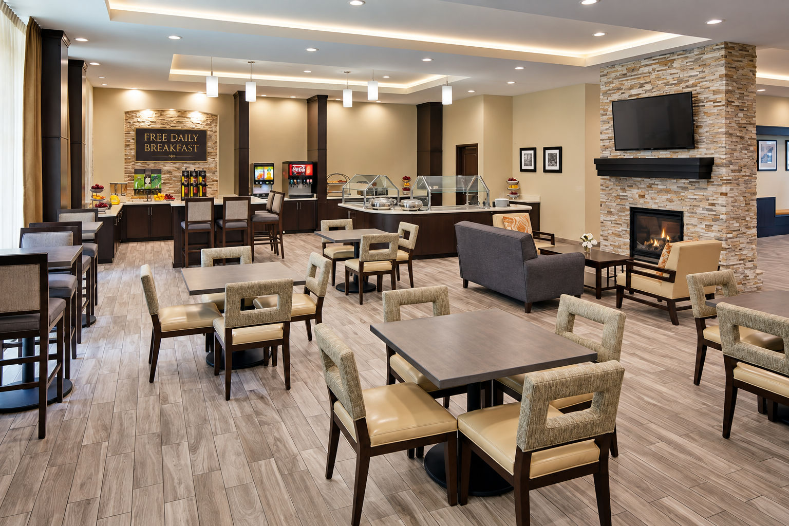 image Spacious dining area with tables and seating for complimentary daily breakfast, with a lounge area and fireplace.