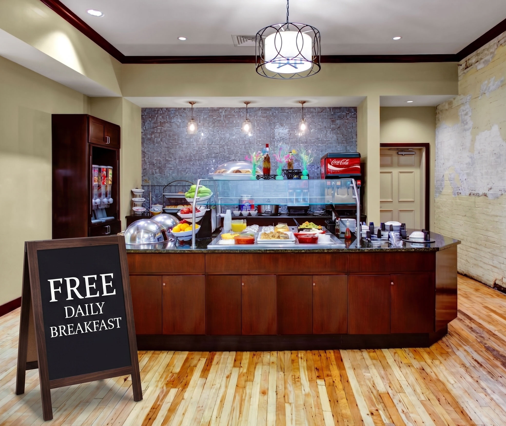 image Complimentary breakfast area featuring a kitchen-style layout with hardwood floors and pendant lighting.