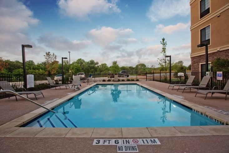 image Outdoor swimming pool with lounge chairs and surrounding trees.