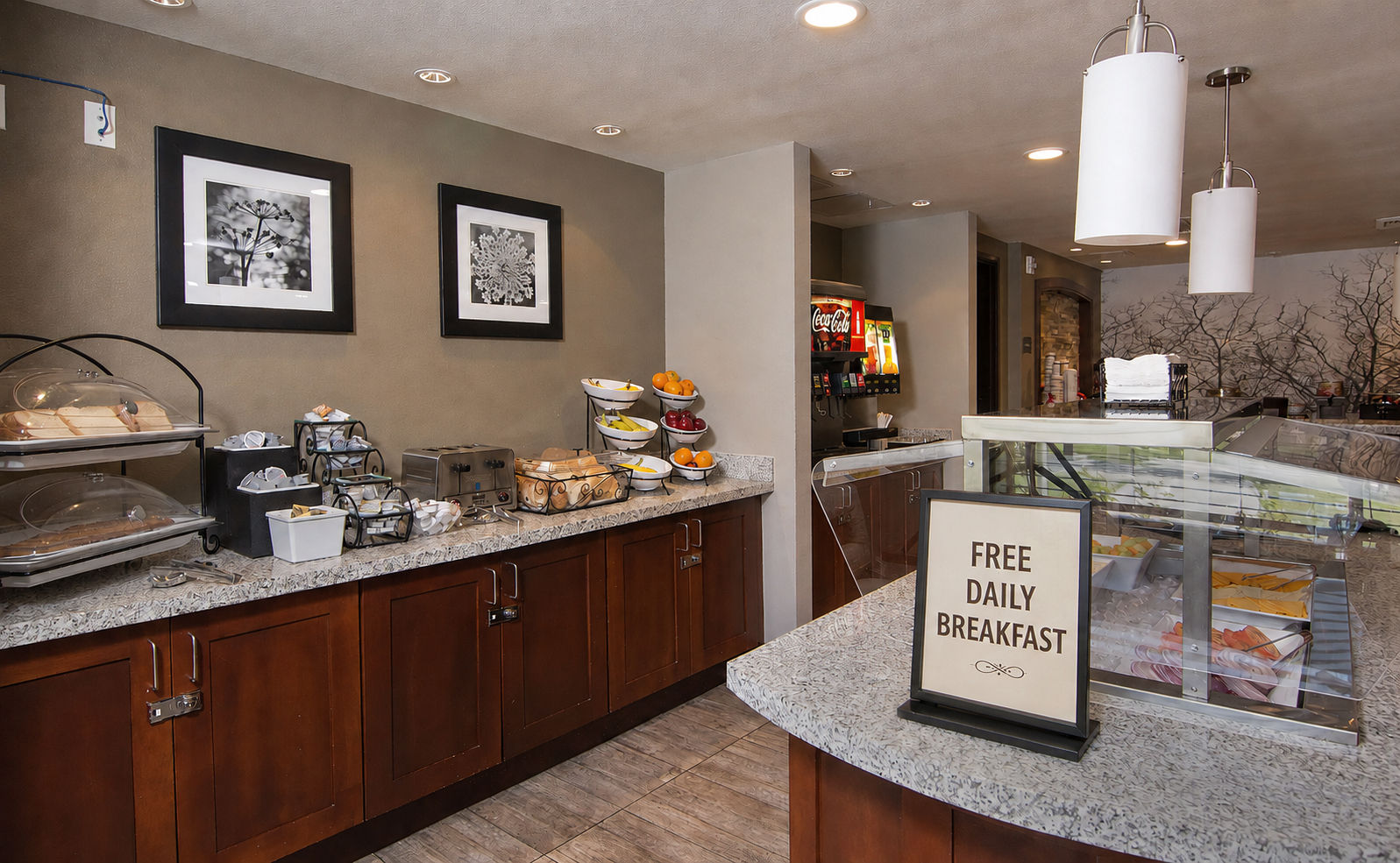 image Breakfast area featuring a variety of pastries and fruits with a sign indicating free daily breakfast.