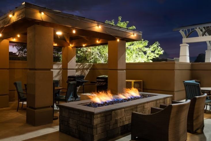 image Gather around the stone fire pit under twinkling lights, enjoying warmth and conversation on the outdoor patio