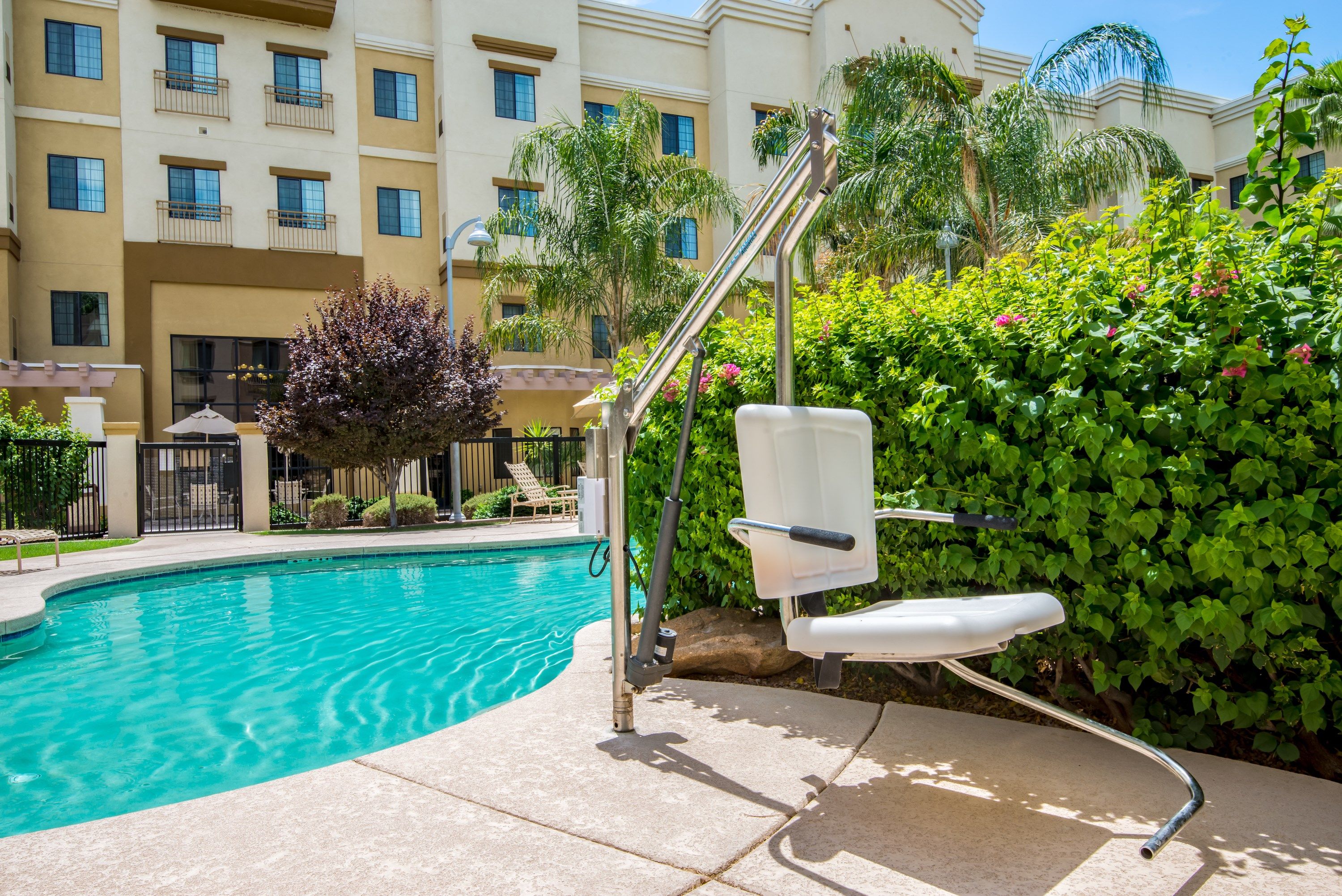 image Accessible outdoor pool with pool lift and lounge chairs.