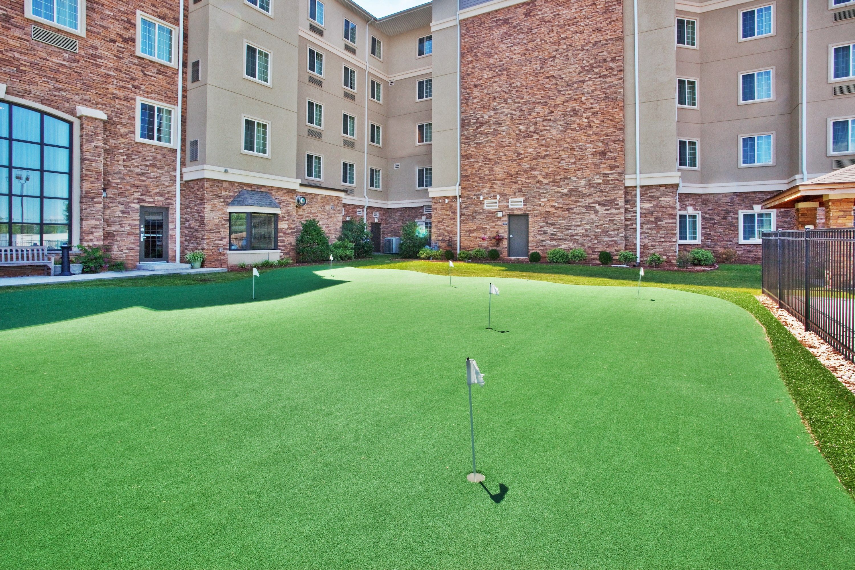 image Putting green with flags outside a building with stone walls.