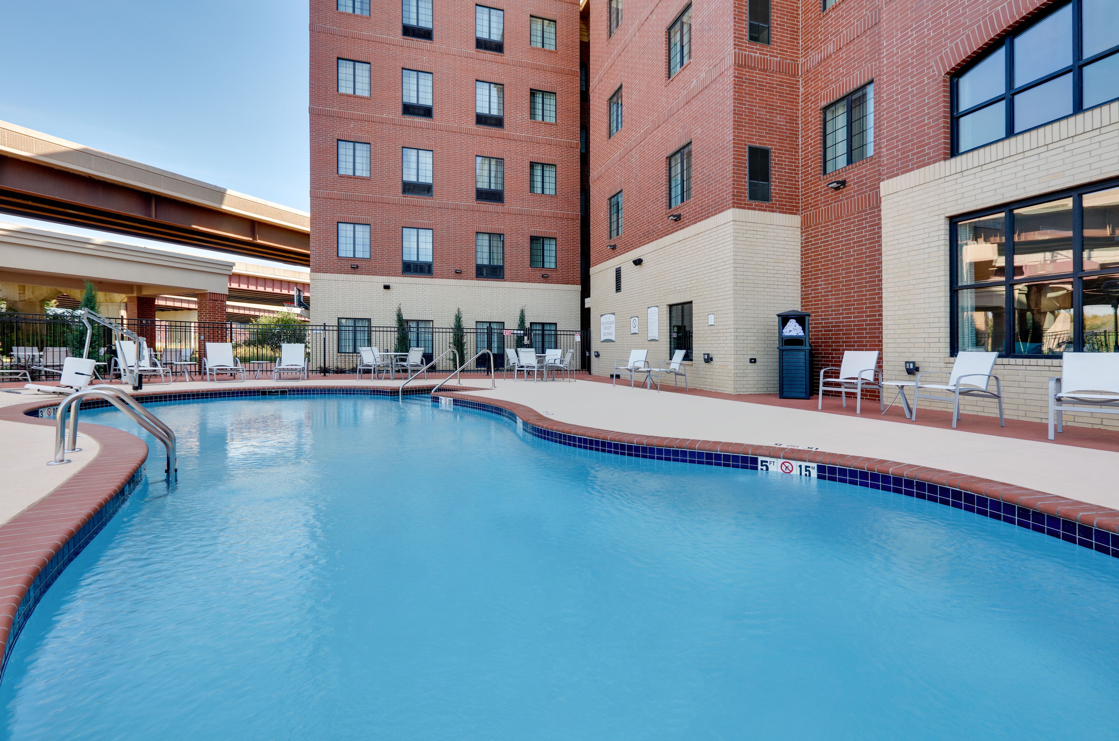 image Sparkling outdoor pool surrounded by comfortable lounge chairs and seating.