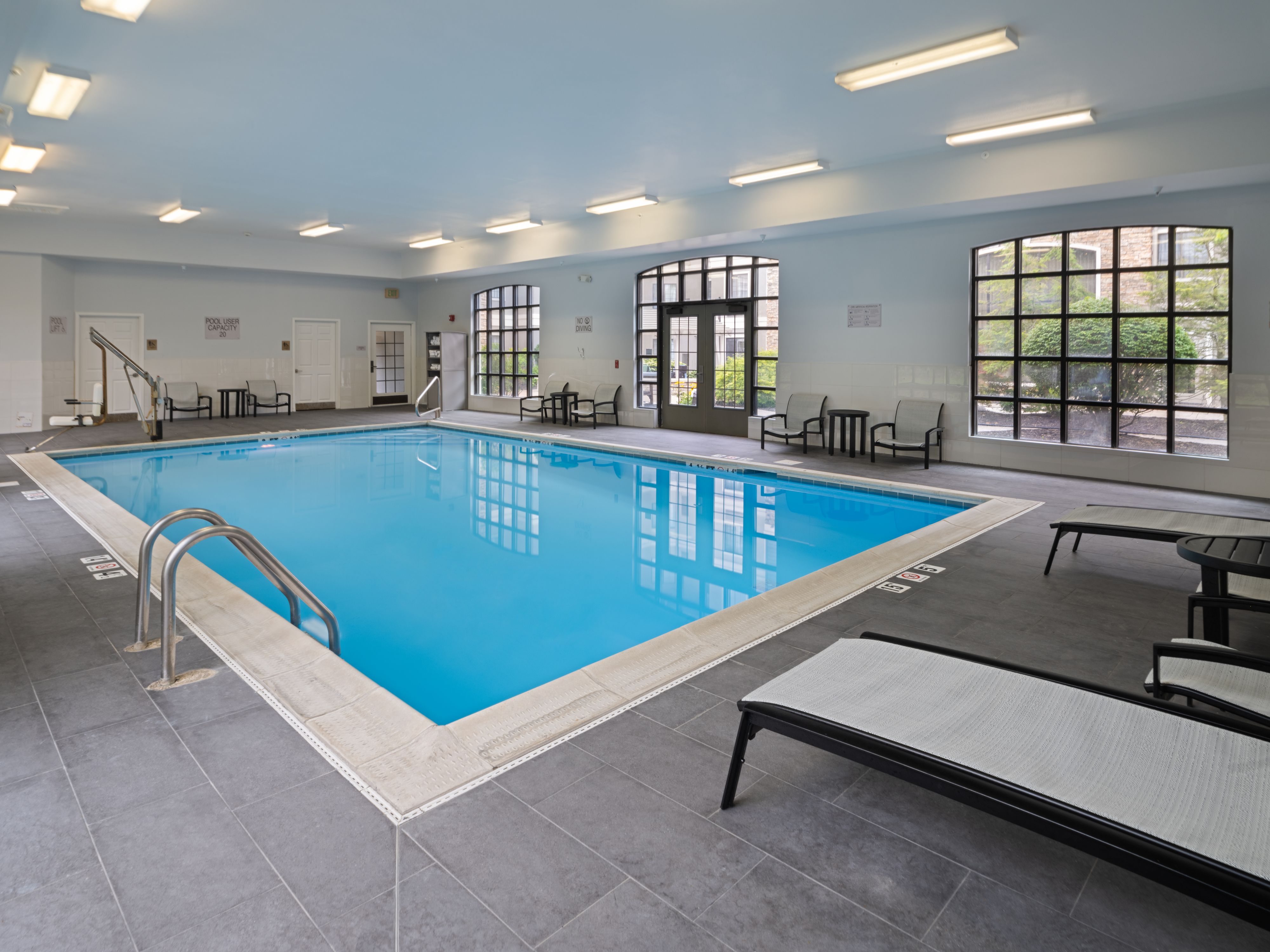 image Indoor swimming pool with lounge seating and warm lighting.