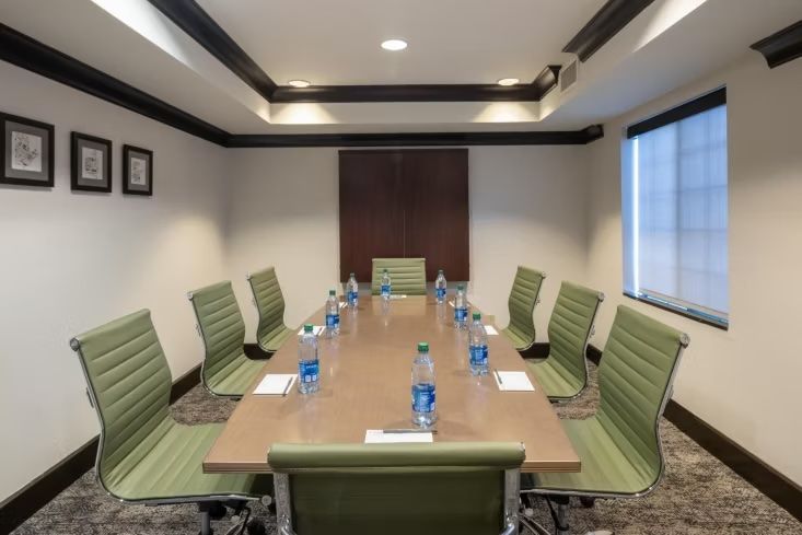 image Conference table surrounded by green chairs and water bottles.