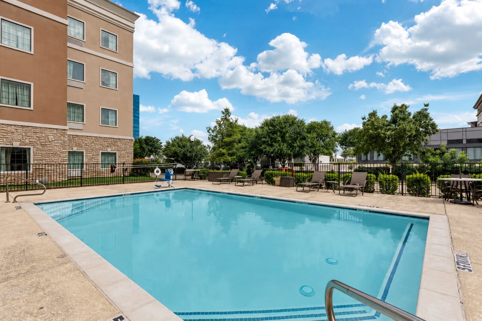 image Take a dip in the seasonal outdoor pool with lounge chairs lined up along the fenced sundeck.