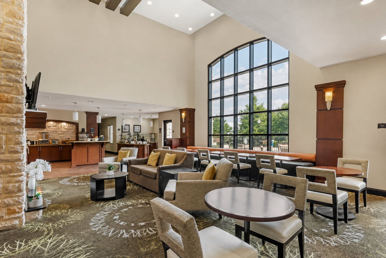 image Floor-to-ceiling arched windows flood the two-story lobby lounge with natural light near the breakfast bar.