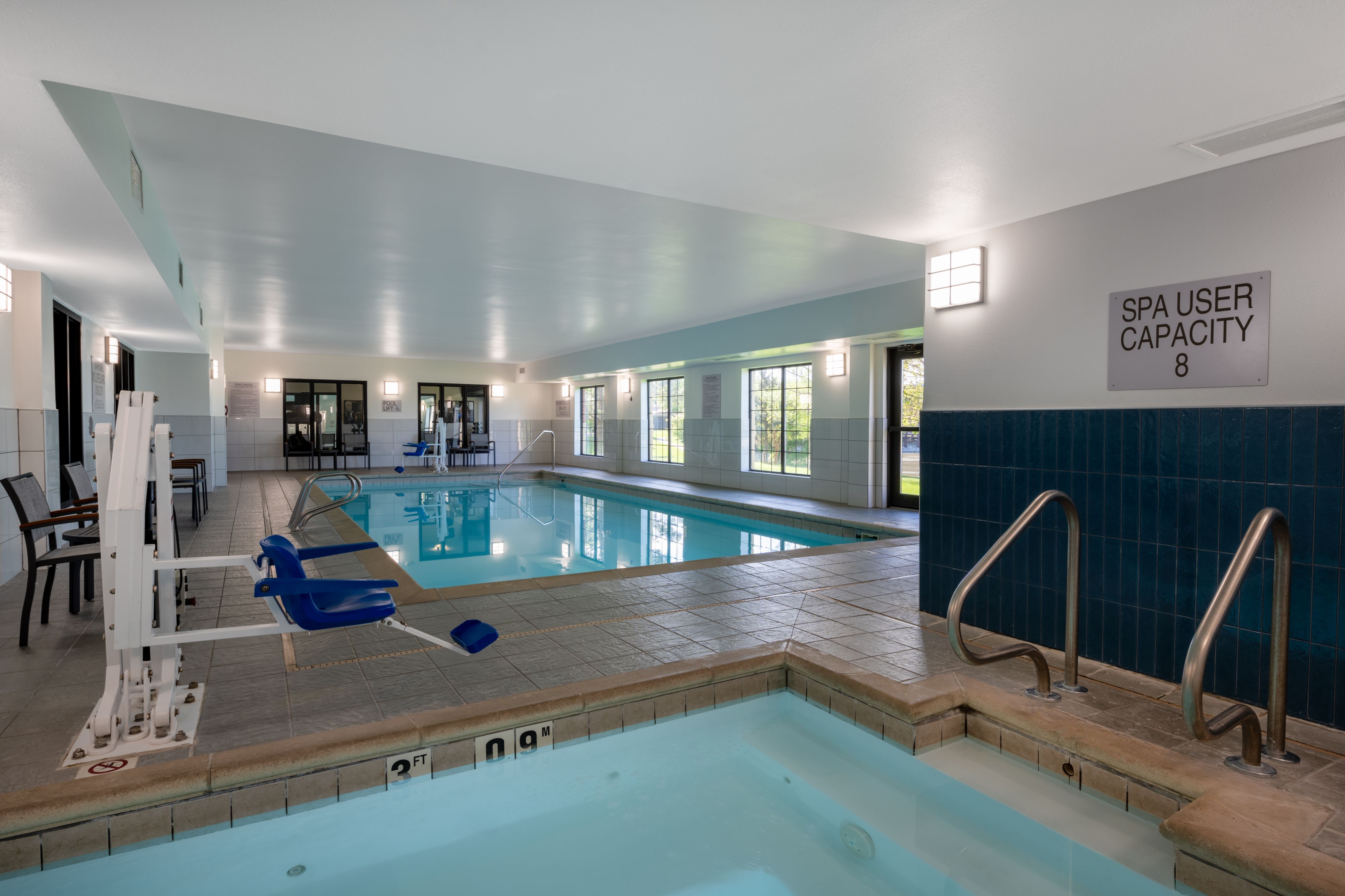image Blue tile accents line the spa entrance beside a full-length indoor pool with poolside seating.
