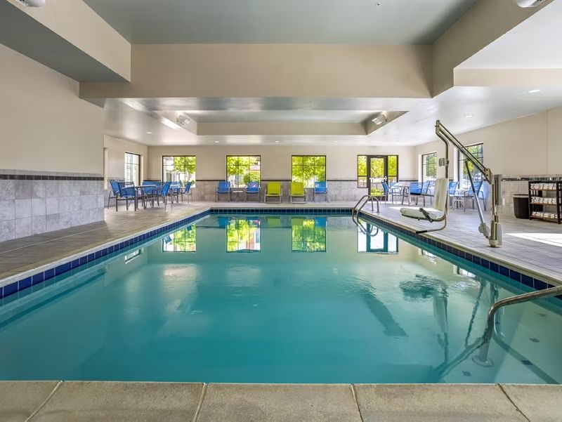 image Cool off and unwind in the sunlit indoor pool, framed by comfortable poolside seating.