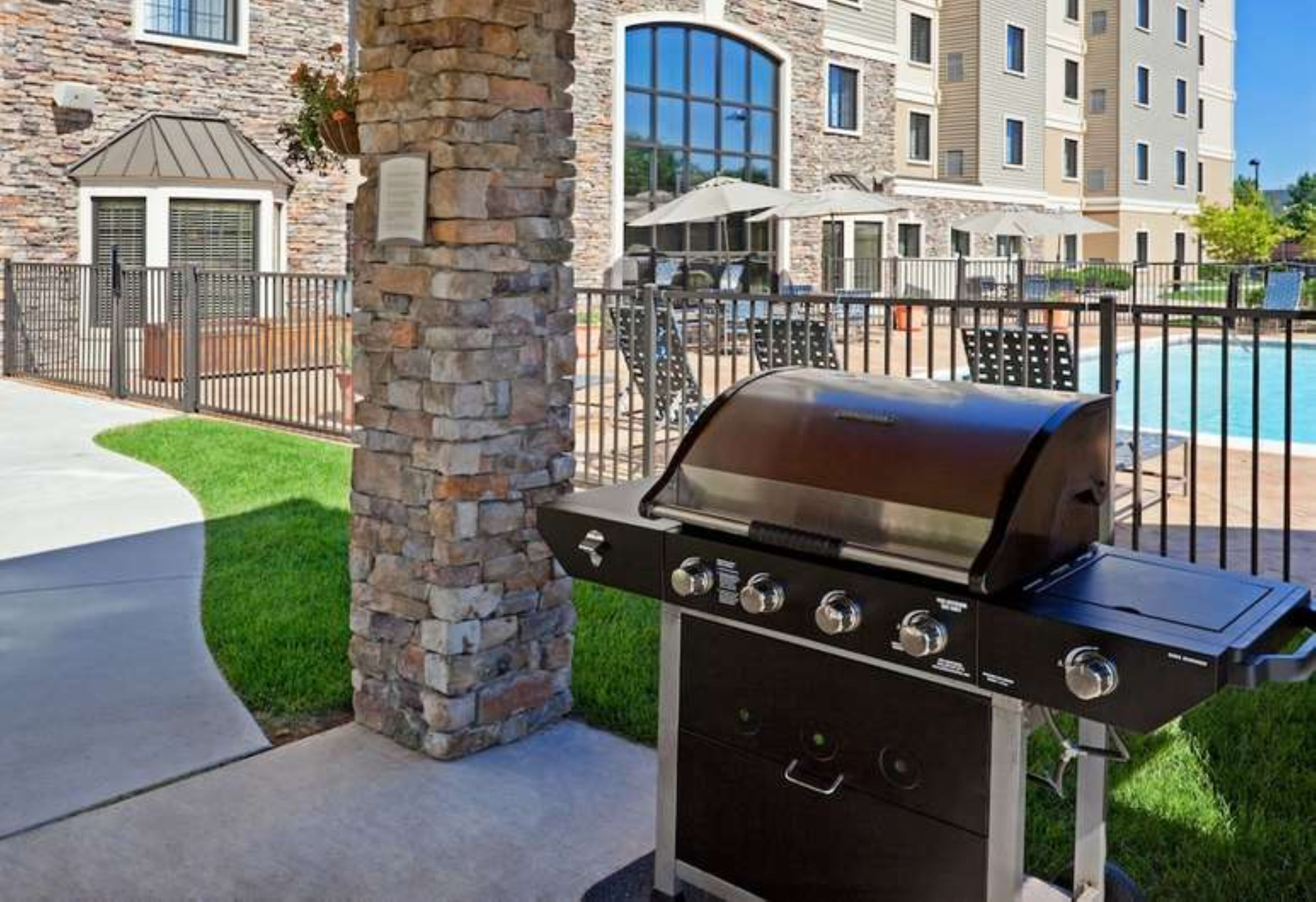 image Outdoor pool area with barbecue grills and lounge seating.