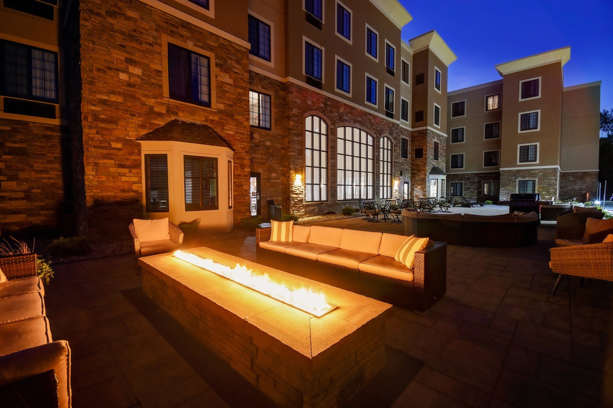 image Evening courtyard with illuminated fire features and modern outdoor seating.