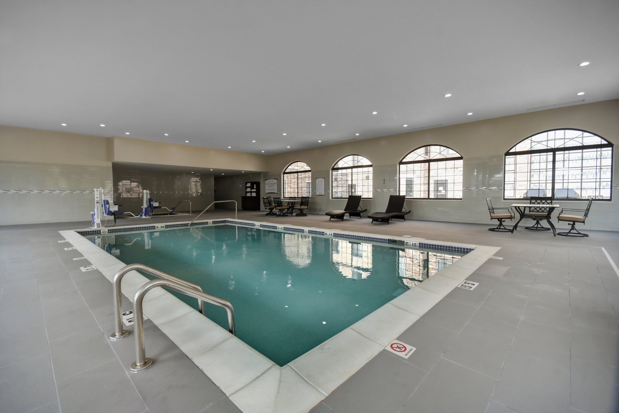 image Indoor pool with accessible entry and surrounding lounge seating for guest comfort.
