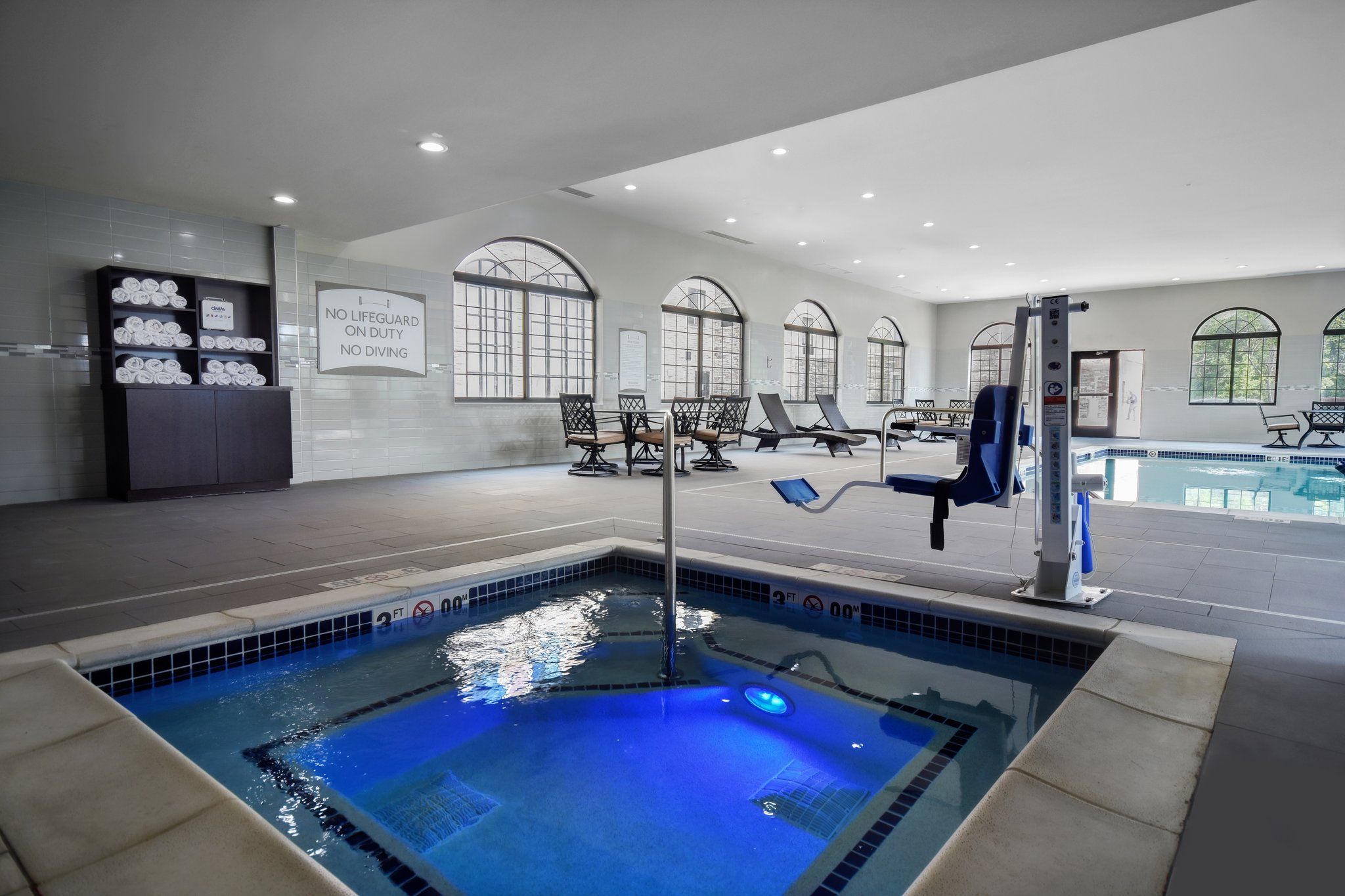 image Indoor pool area with a hot tub and seating for relaxing after a long day.