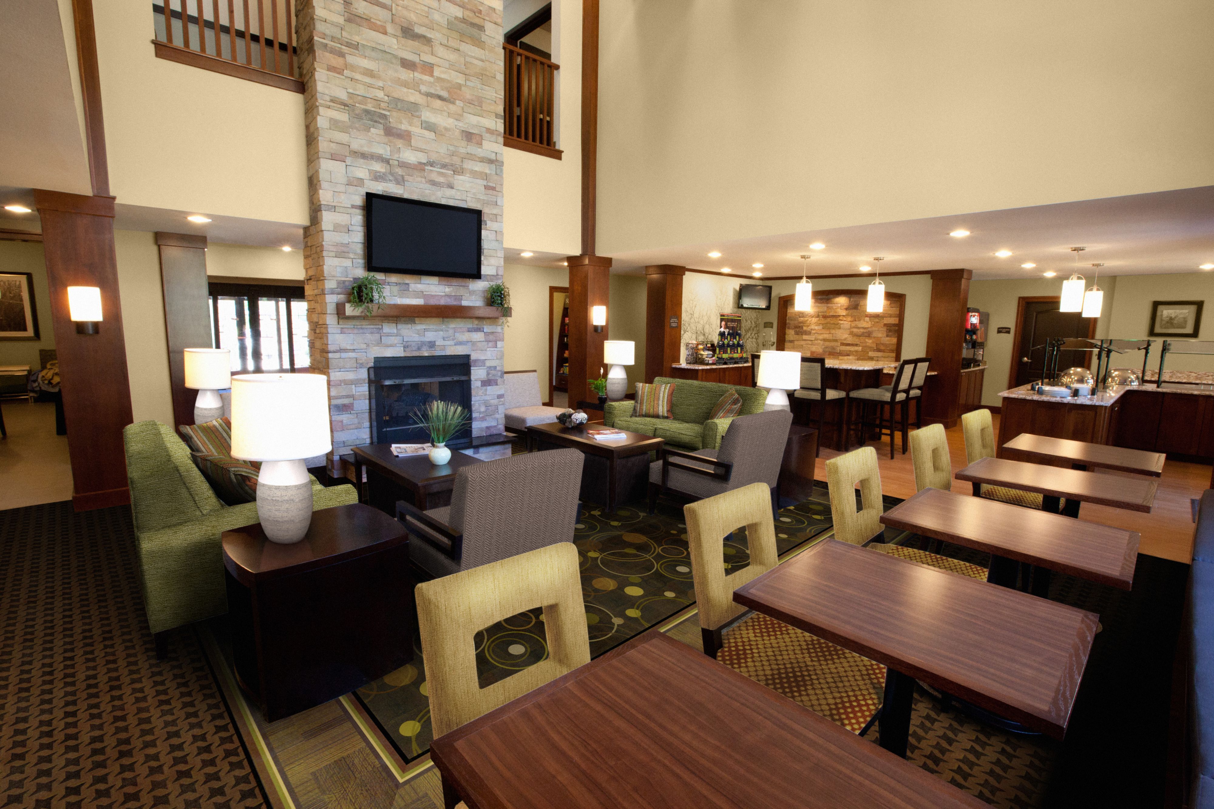 image Spacious lobby featuring a stone fireplace, comfortable seating, and adjacent breakfast area.