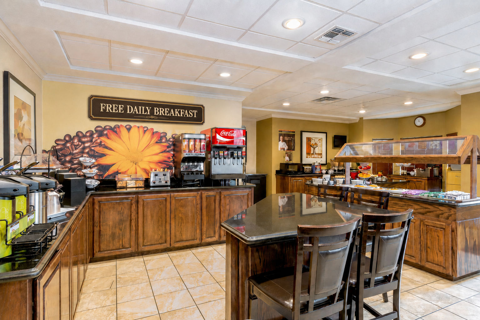 image Complimentary breakfast area with a coffee station, juice dispensers, and buffet-style setup featuring various food items and seating options