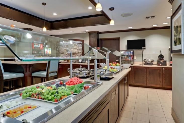 image Breakfast buffet area with food displays, beverage station, and counter seating.
