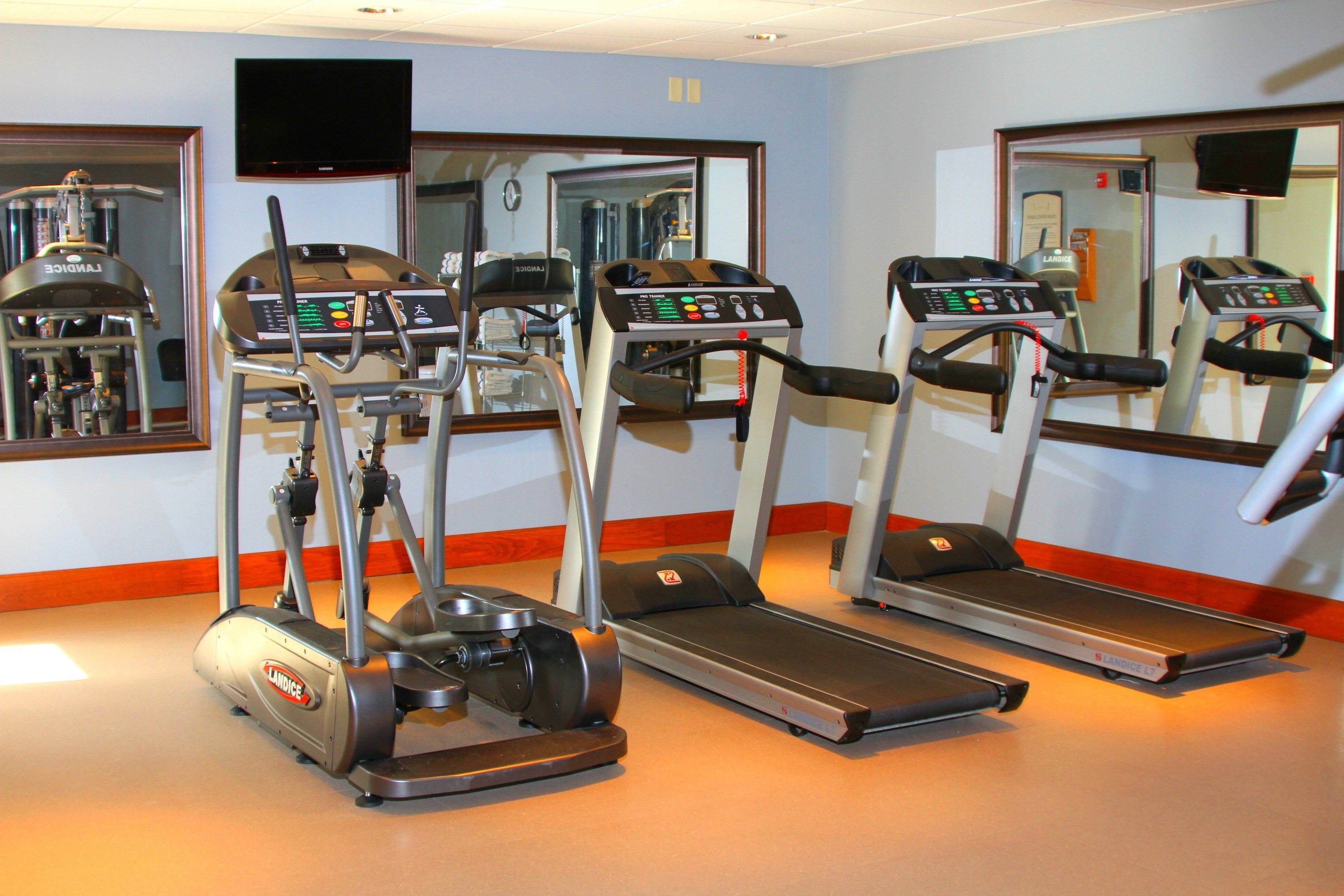 image Fitness center with cardio equipment and mirrored walls.