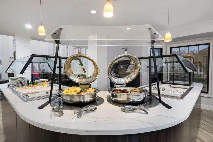 image Breakfast buffet station with chafing dishes of fresh fruit and breakfast meats under glass covers