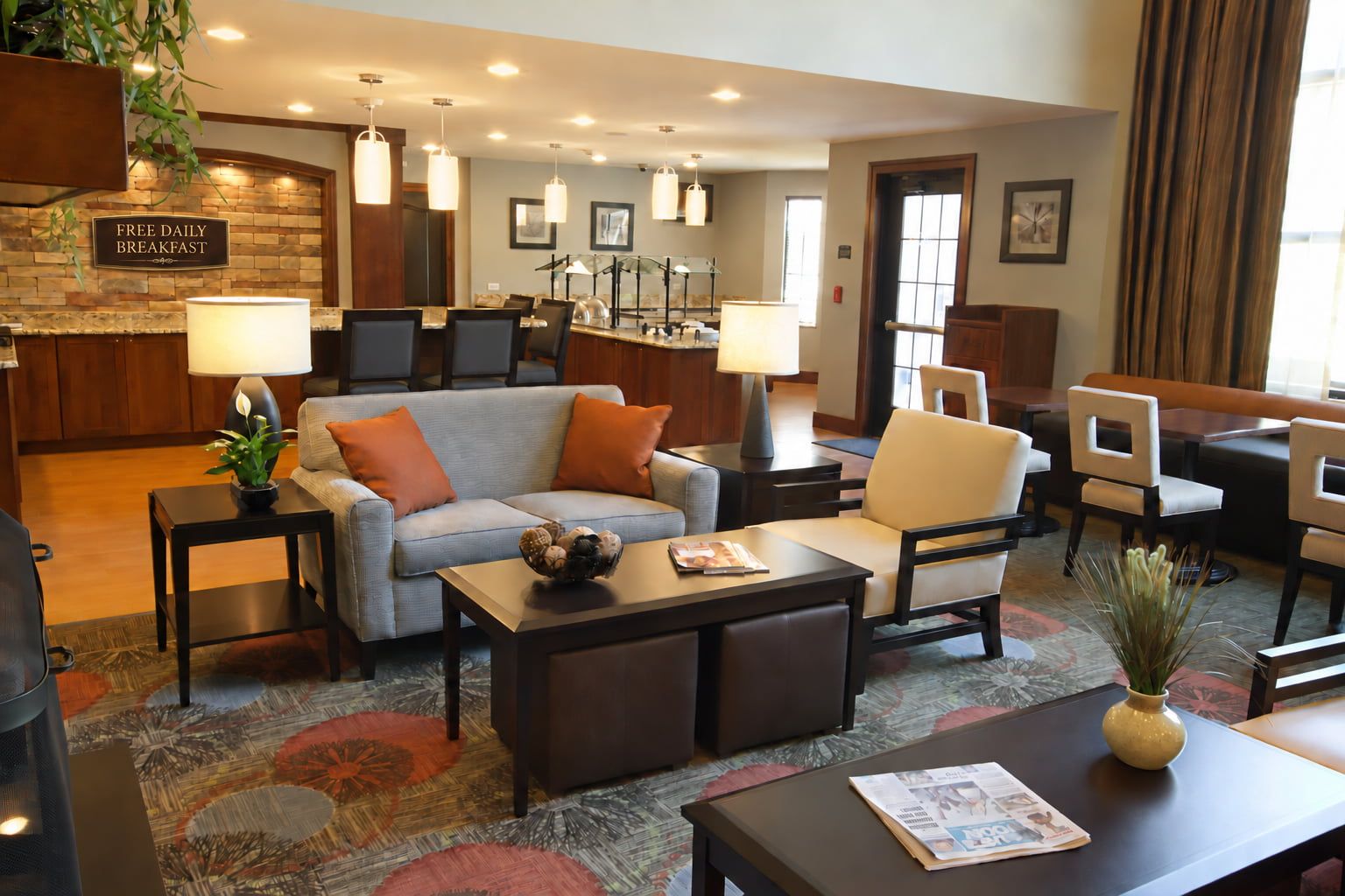 image Lounge area with a gray sofa, armchair, and coffee table beside a granite counter.