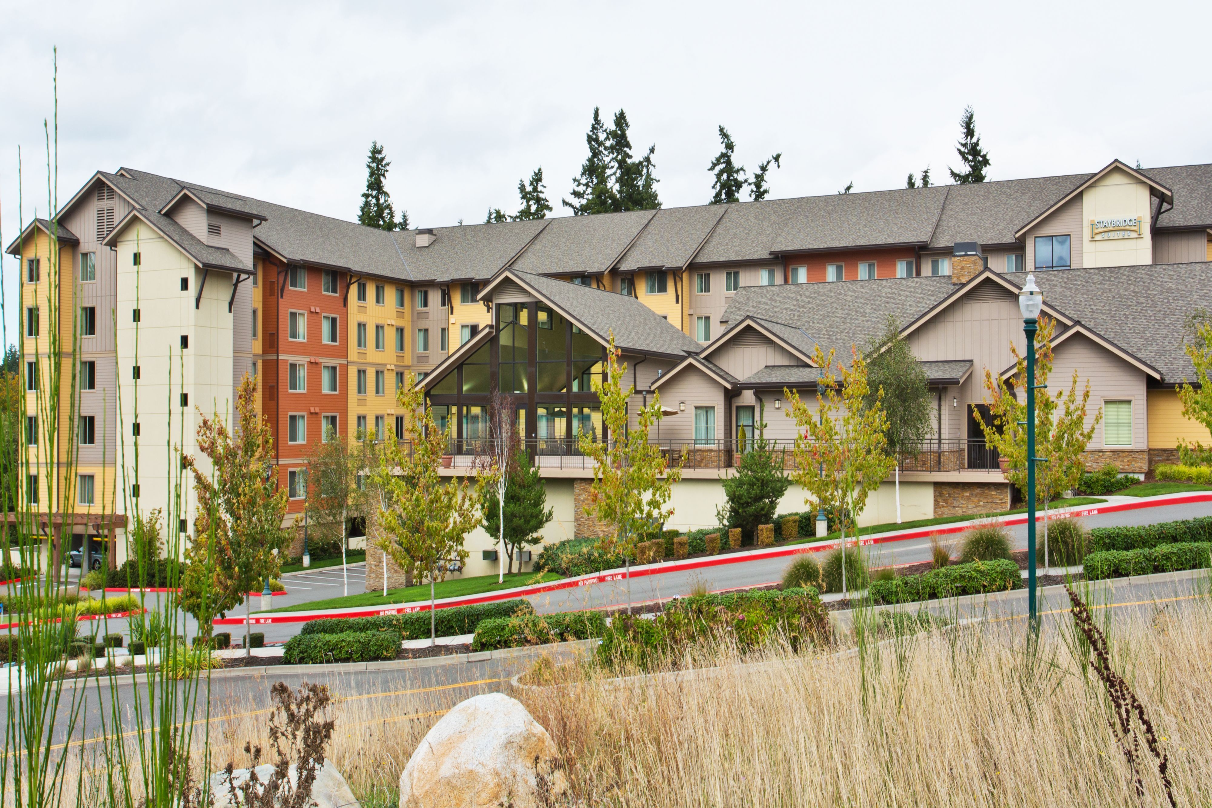image Earthy stone and wood tones define the building's exterior amid mature landscaping