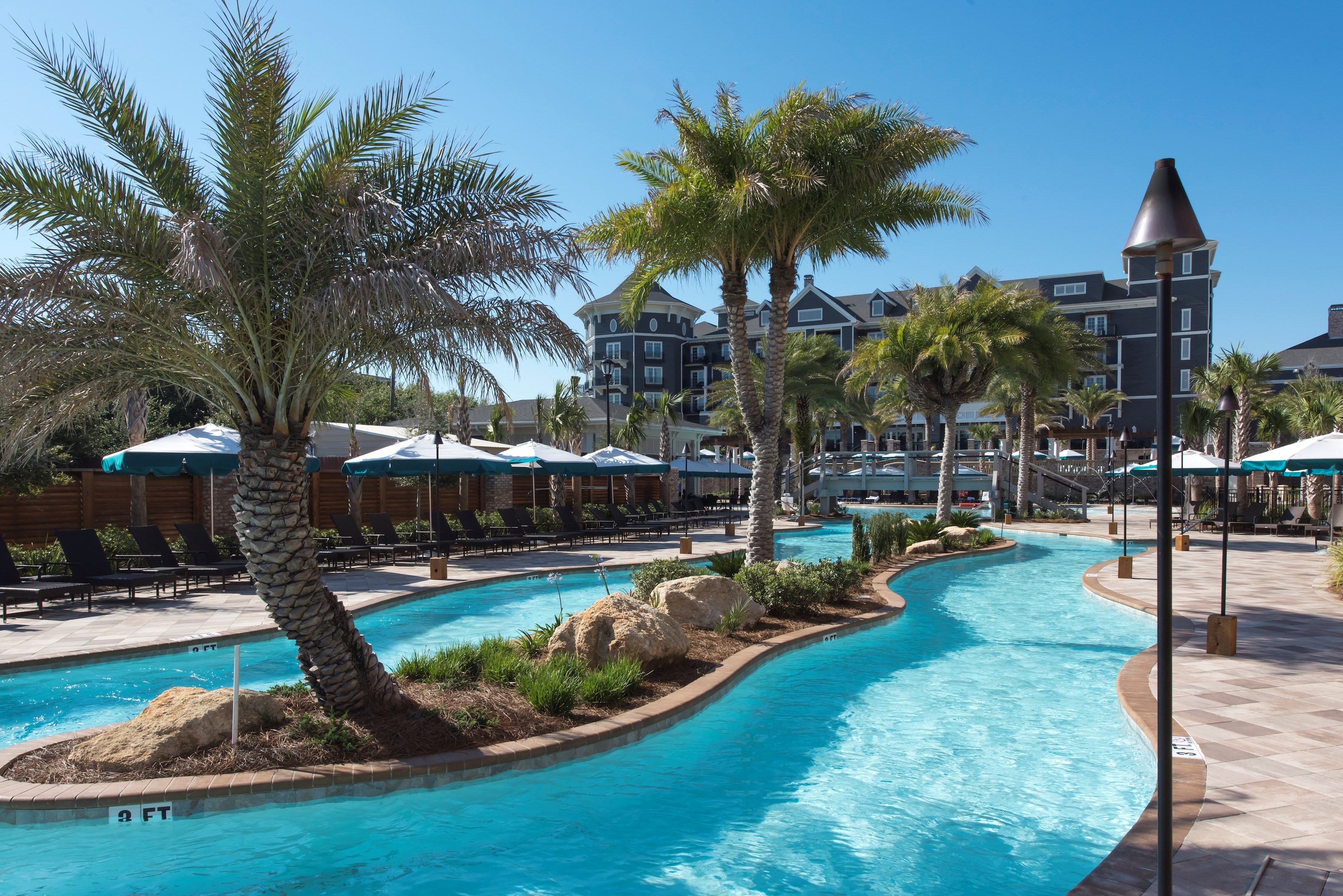 image Winding resort pool with tropical landscaping, perfect for leisurely swims.