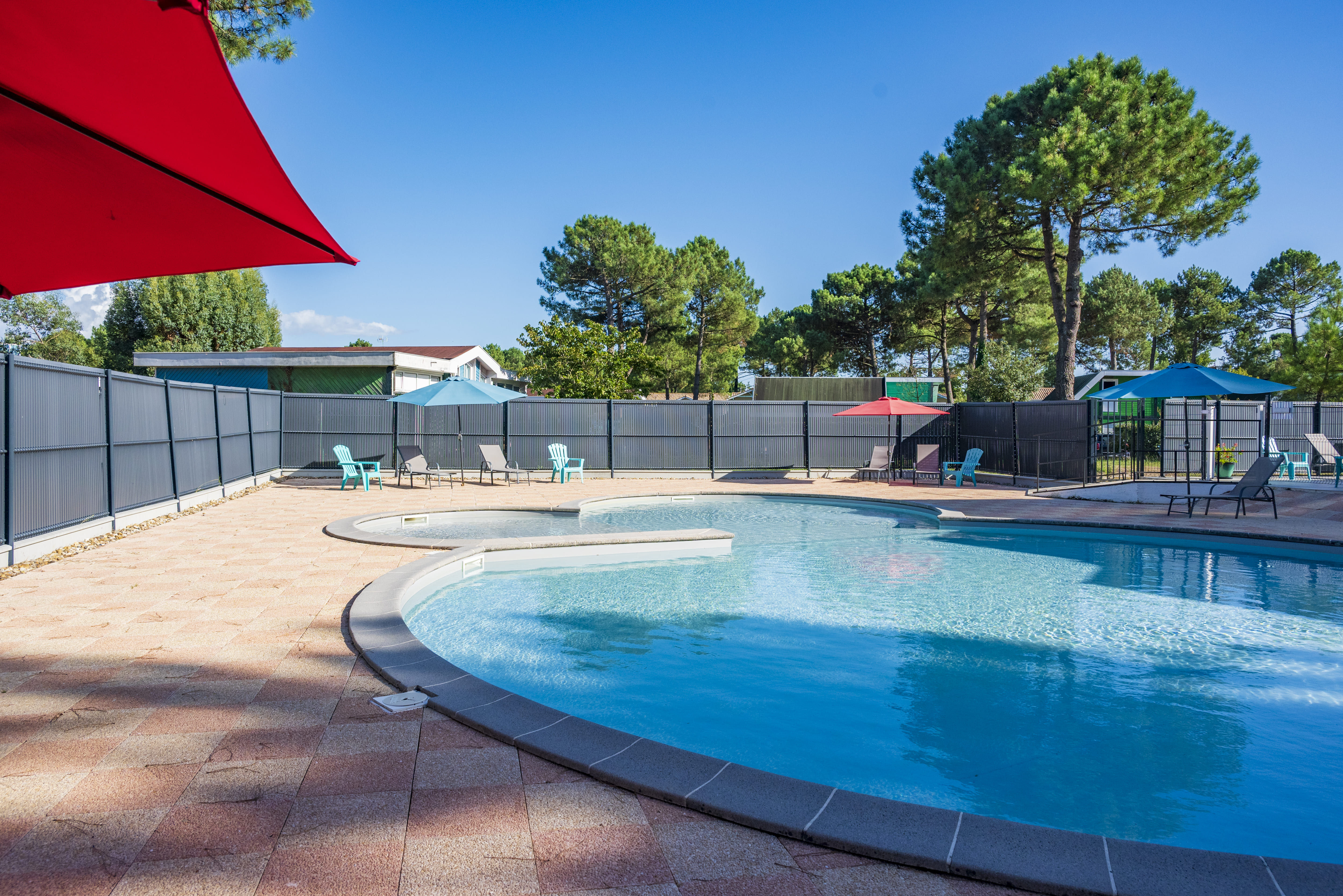 image Cool off under the red shade sail beside the round outdoor pool.