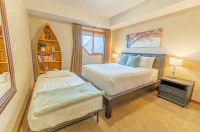 Bedroom with a king bed, a movable twin bed, shelf, and decorative items
