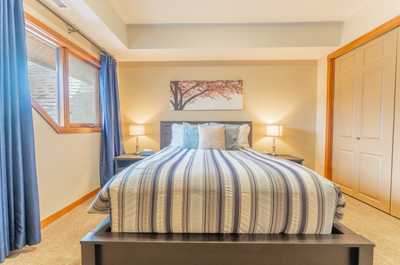 Comfortable guest bedroom with striped bedding and ample natural light.